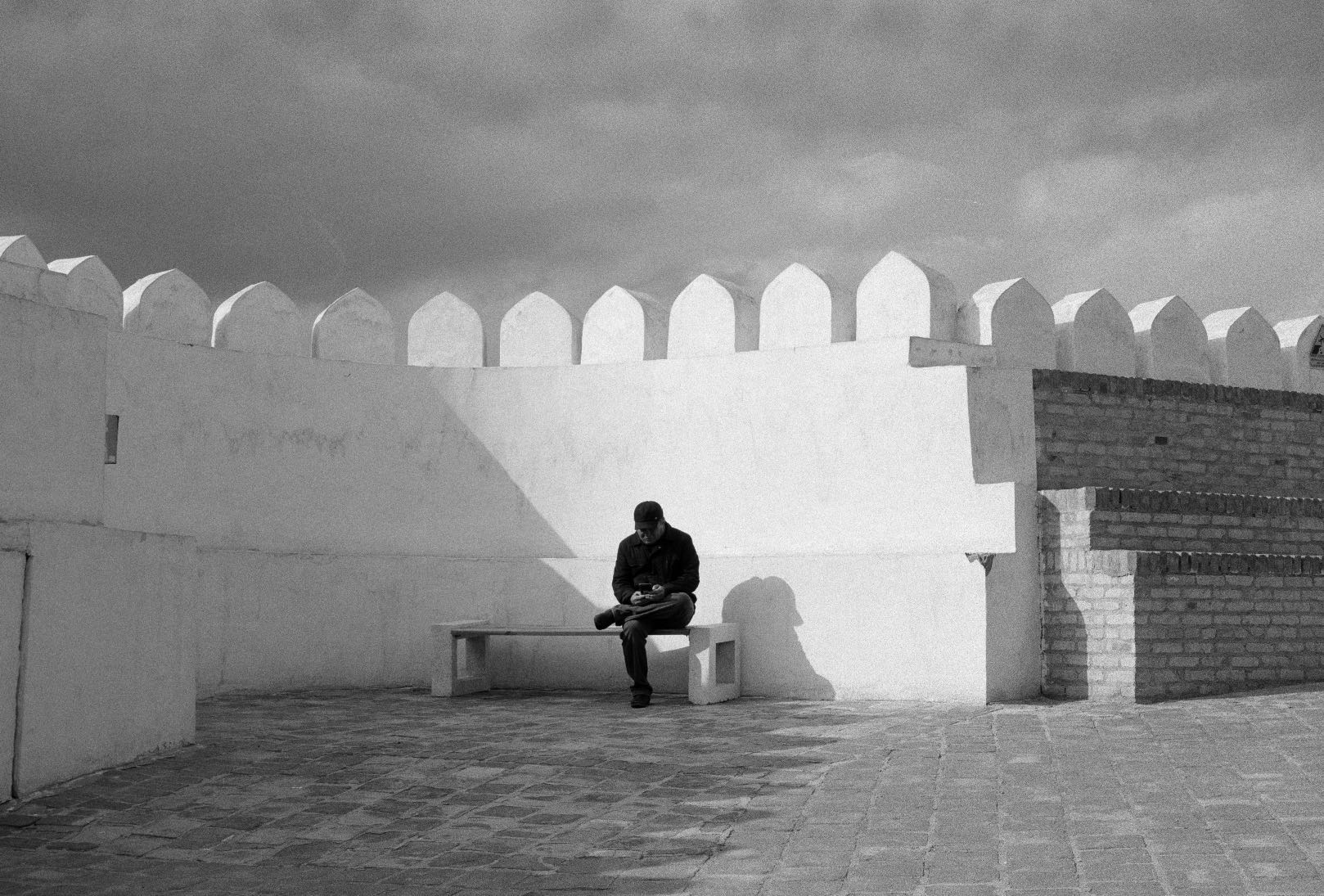 Black-and-white photograph: A man sitting in the restored sections of the Arc of Bukhara, Bukhara, Uzbekistan, 2024